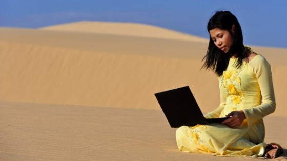 Young-Asian-woman-in-Yellow-Ao-Dai-with-a-laptop-in-the-dunes-via-Shutterstock-615x345