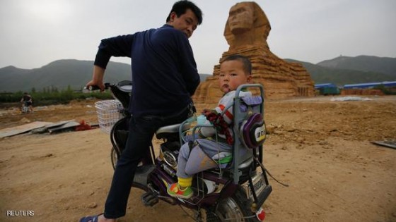 A man and a boy on an electric bicycle look back as they visit a full-scale replica of the Sphinx, that is part of an unfinished theme park that will also accommodate the production of movies, television shows and animation, in Shijiazhuang