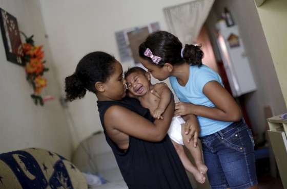 Maria Clara and Camile Vitoria hold their brother Matheus, who has microcephaly, in Recife, Brazil